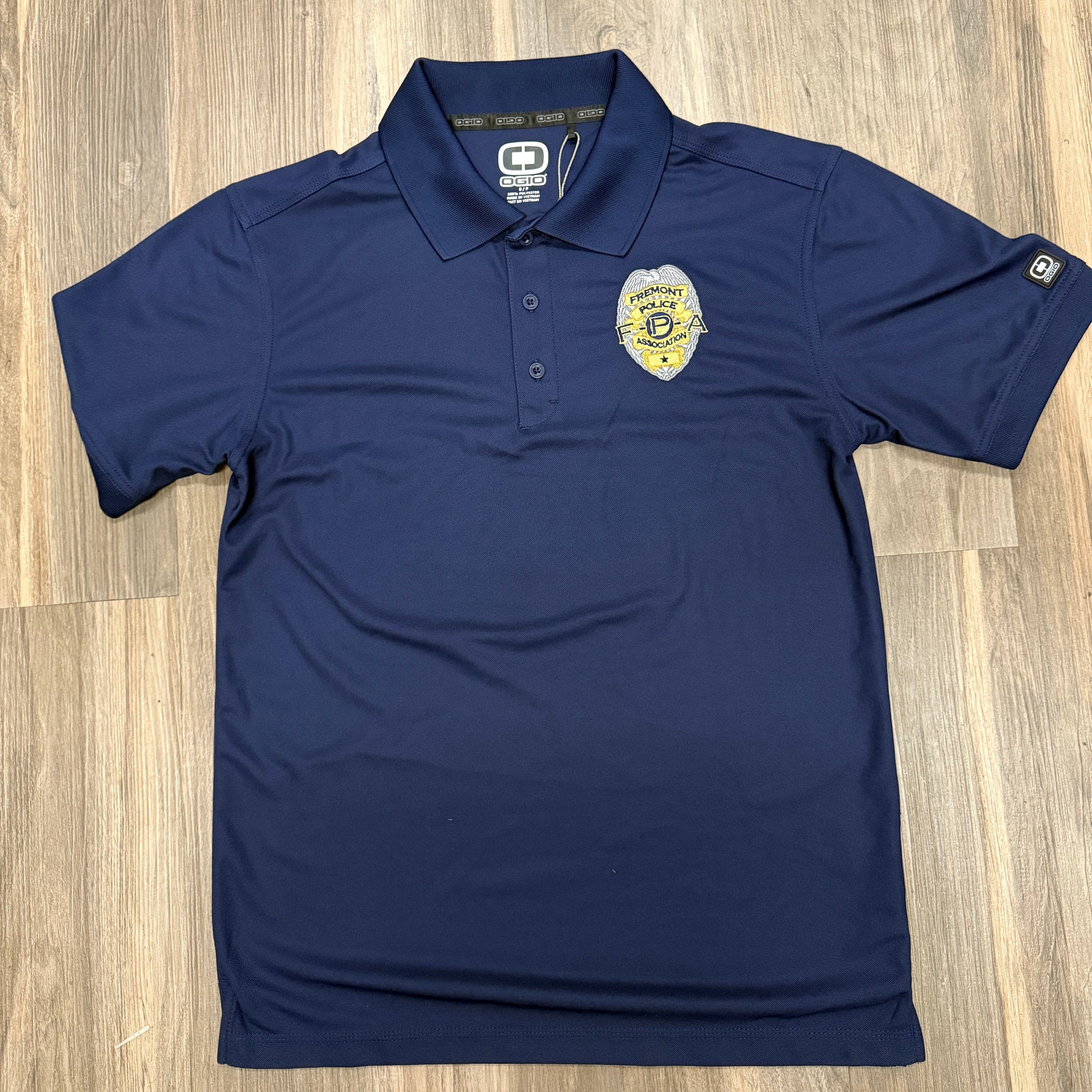 Navy blue polo shirt with a logo on a wooden surface